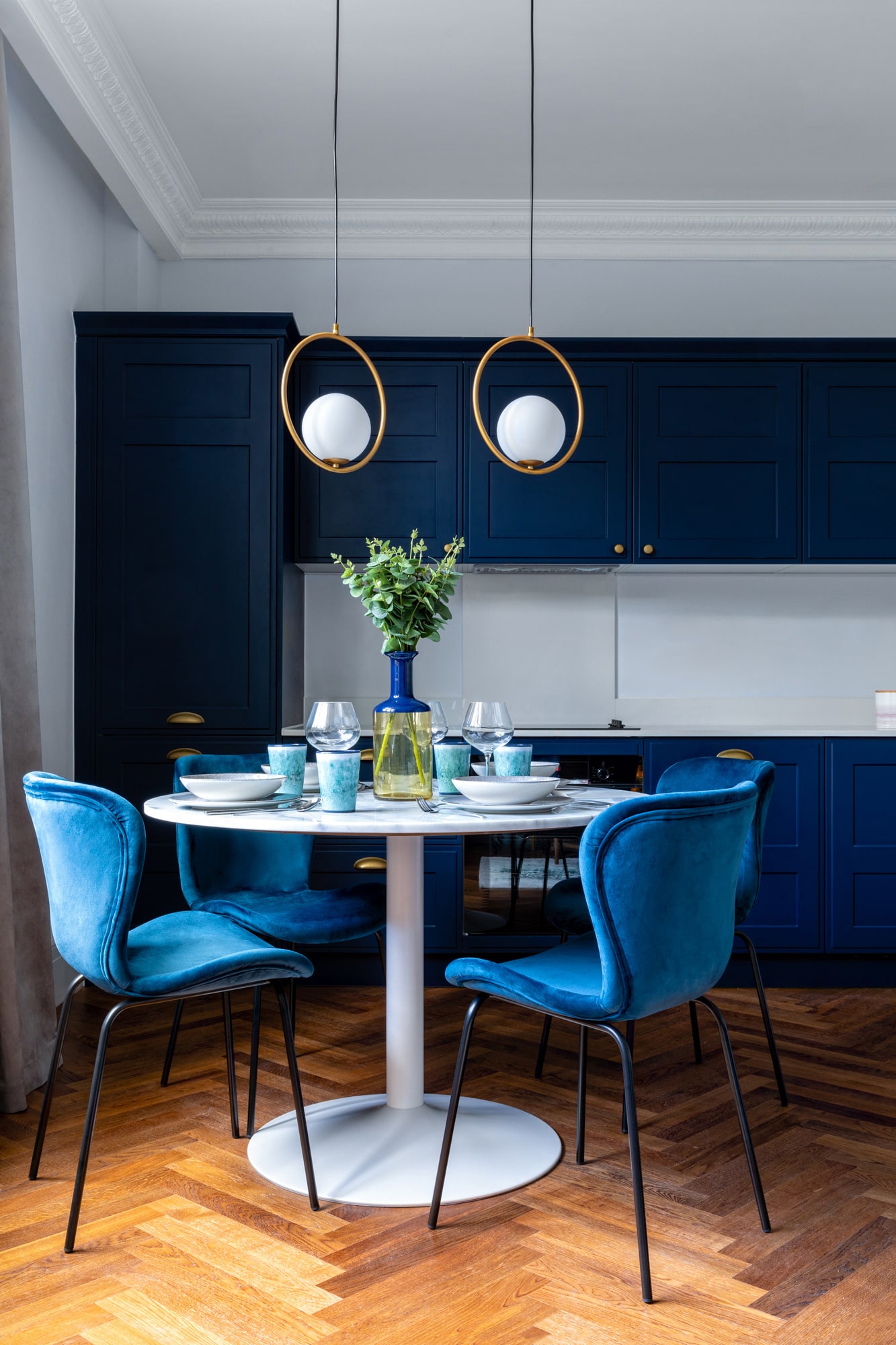 Interior design photography of a kitchen with navy blue facades, marble table and velvet blue chairs 