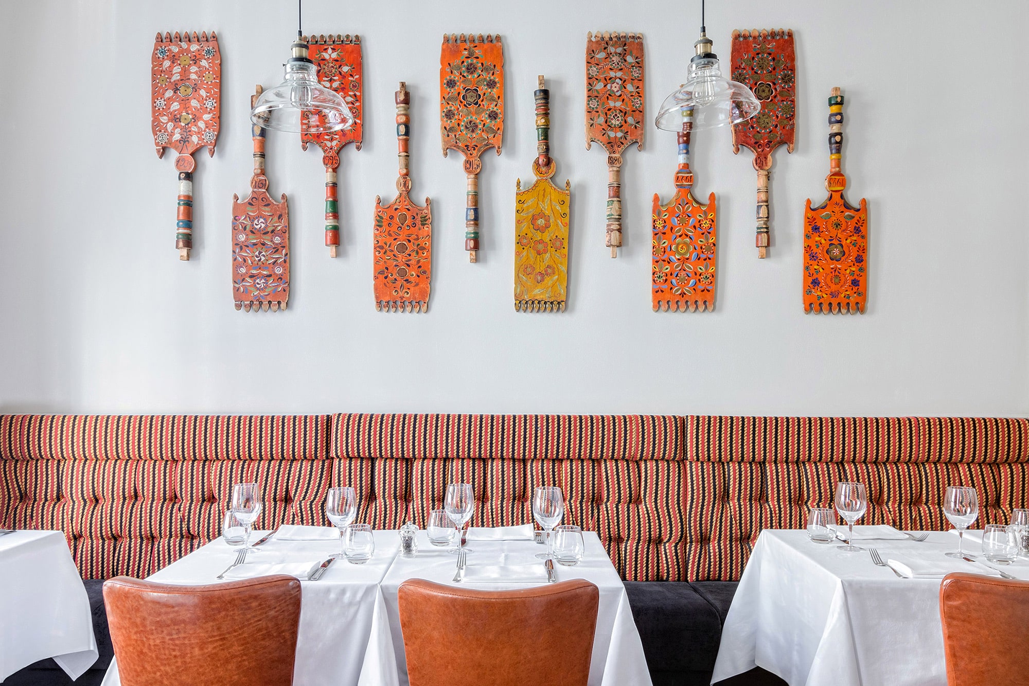 Interior photo of a Russian restaurant: orange leather chairs; tables with white cloths; traditional old Russian decor on the wall