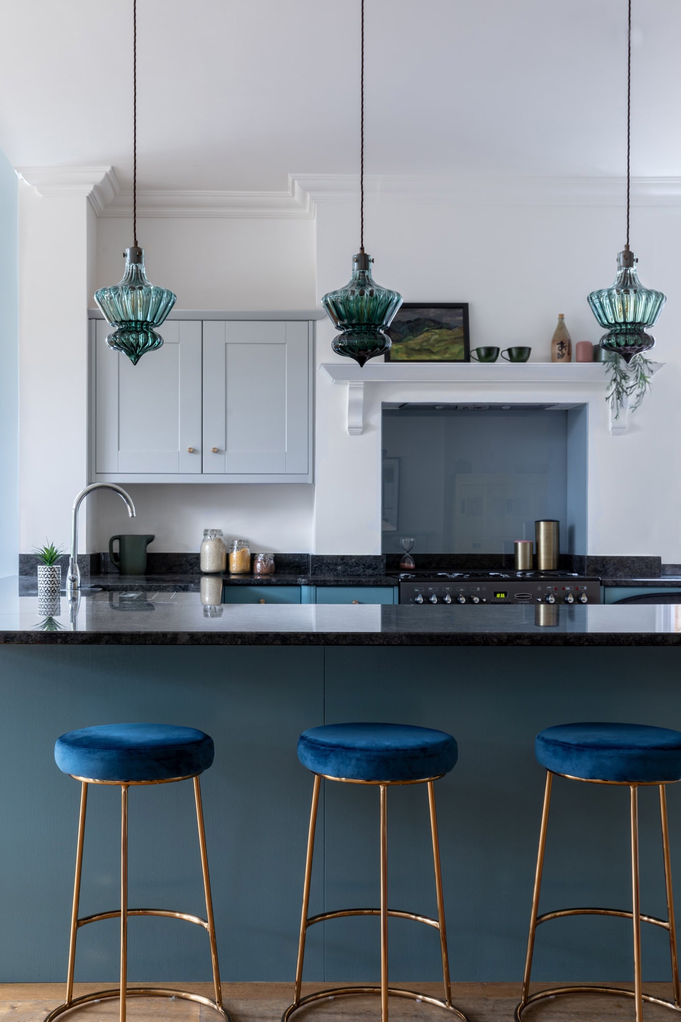 Blue kitchen with round blue velvet bar stools; three blue hanging lights