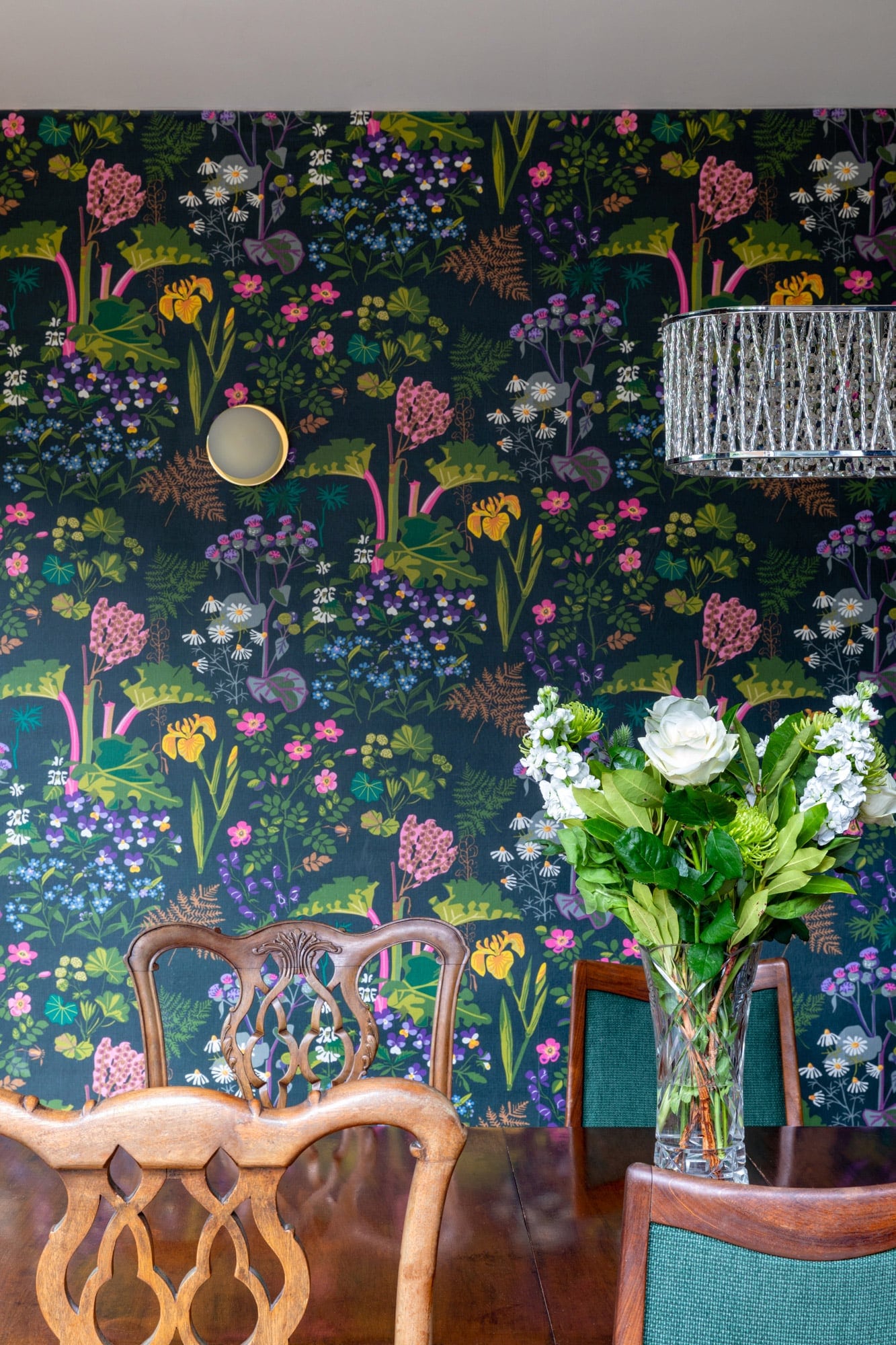 Interior detail shot of a dining table with vibrant wallpaper on the background