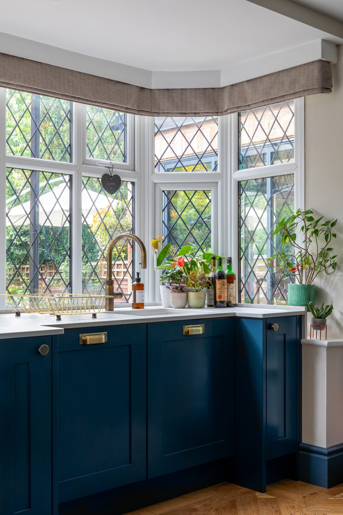 Detail of navy blue kitchen, sink with a window on the background