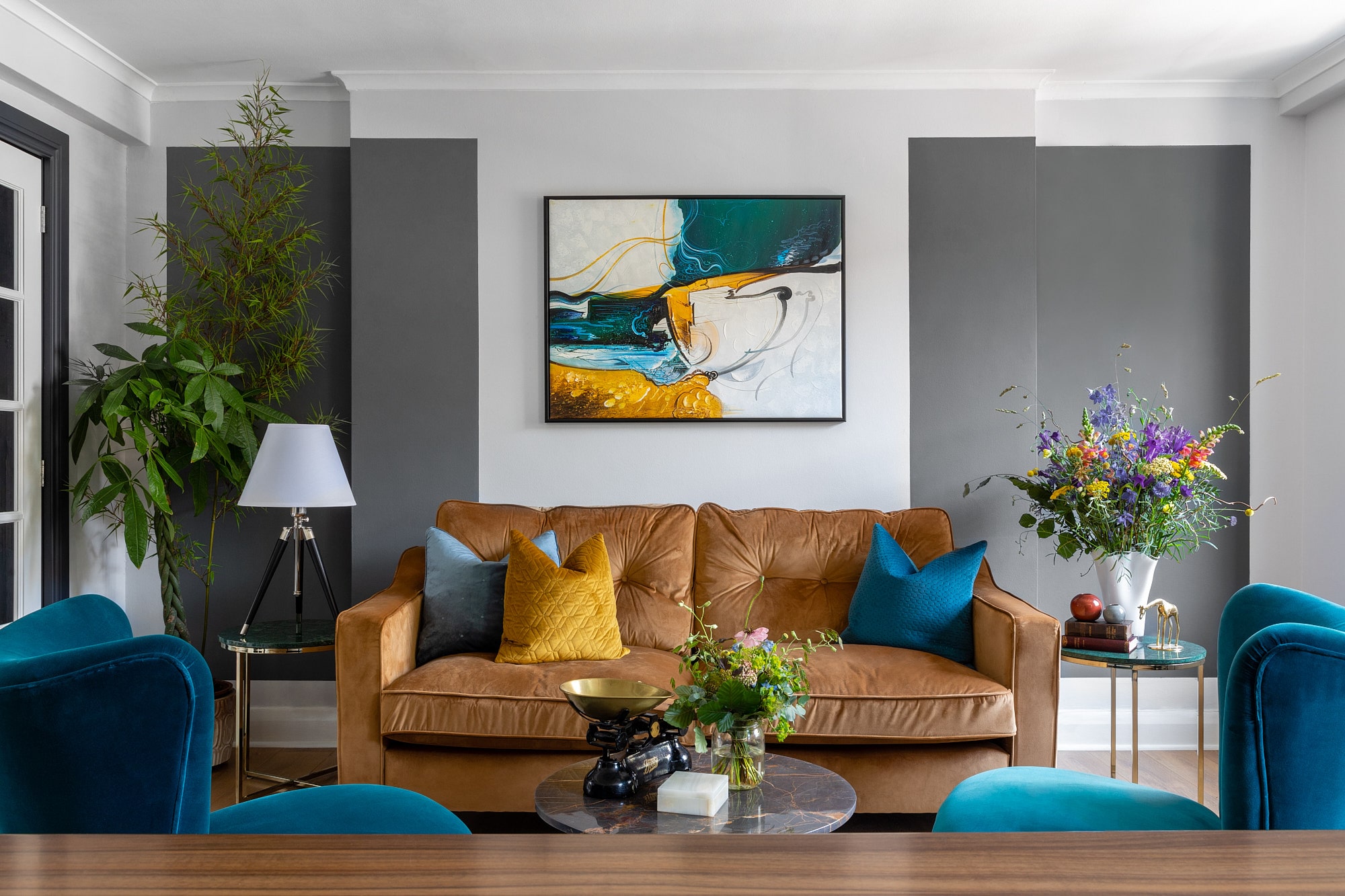 yellow sofa with yellow and blue pillows, art on the wall and armchairs