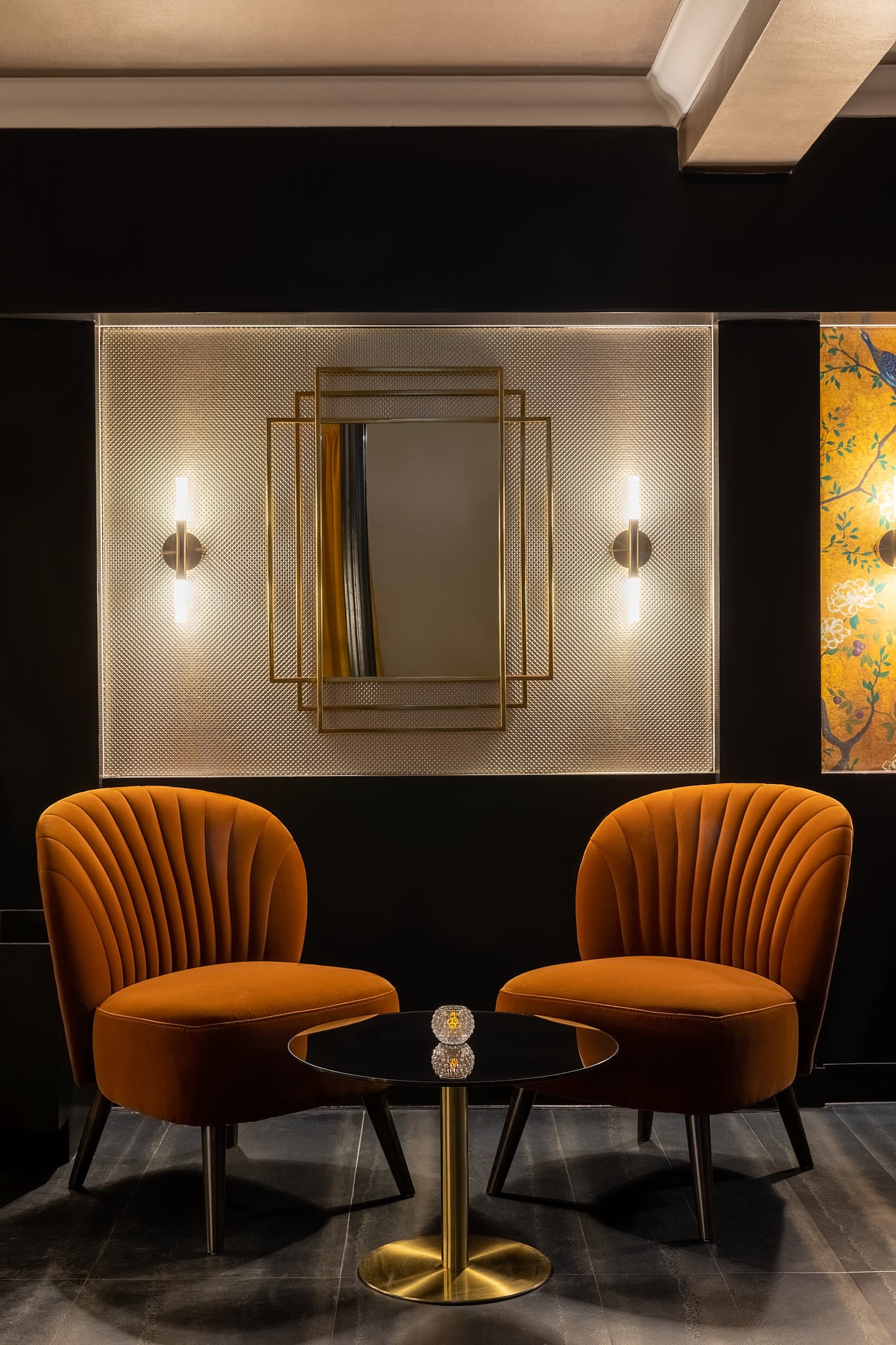 two velvet armchairs in a dark room with a mirror and wall lights