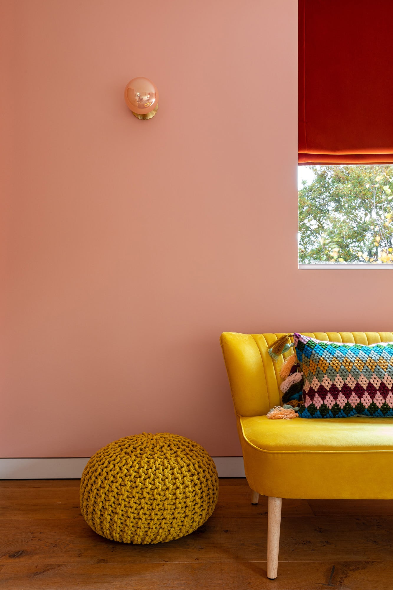 girl's bedroom with a yellow sofa and poof, window and roller blinds