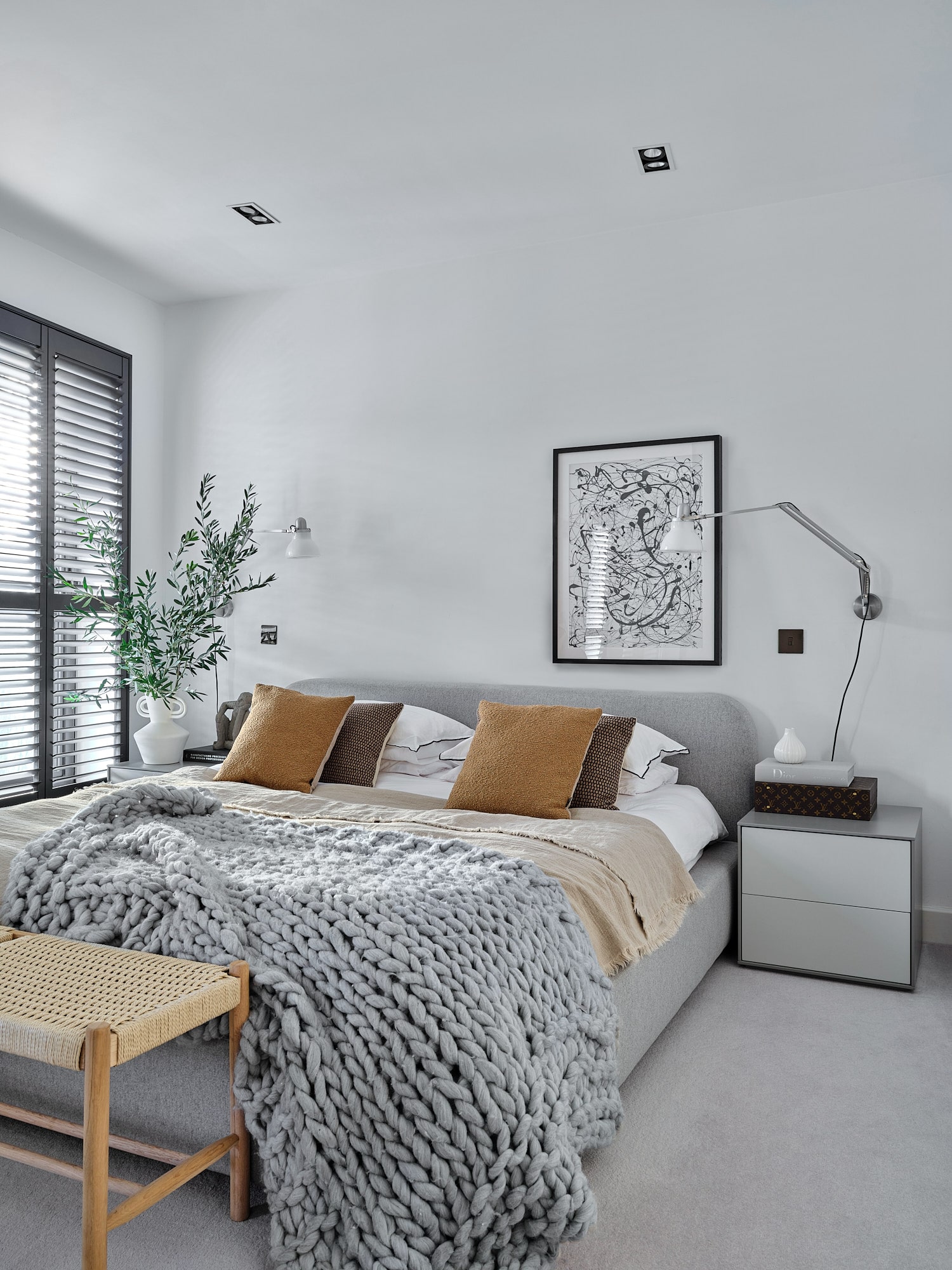 bedroom with white walls, grey bed, shutters, bedside table in minimalist style